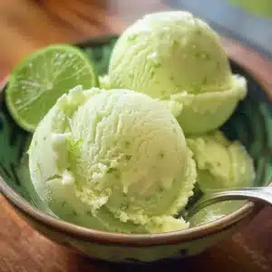 Bowl of vibrant green lime sherbet topped with lime slices.