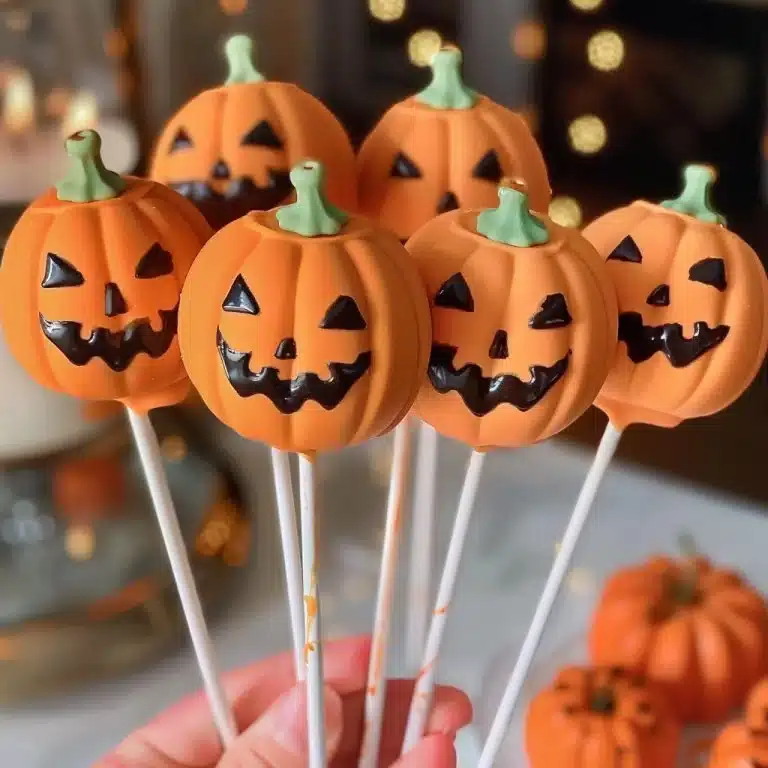 Halloween Jack-O'-Lantern Cake Pops 🎃🍰Adorable Pumpkin-Shaped Cake Pops Coated in Bright Orange Chocolate, Decorated with Spooky Jack-O'-Lantern Faces, and Finished with Cute Green Stems for the P...
